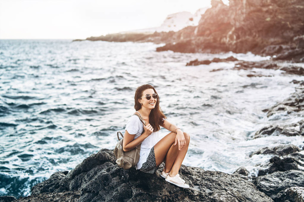 Pretty long hair tourist girl relaxing on the stones near sea. - Foto, Bild