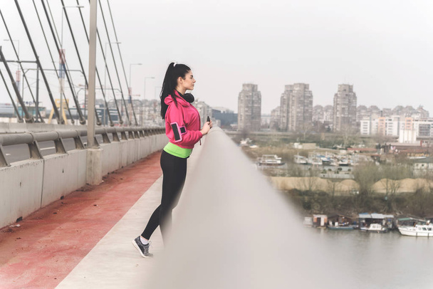 Приваблива спортивна молода жінка досягла щоденної мети тренування і насолоджується видом на річку
 - Фото, зображення