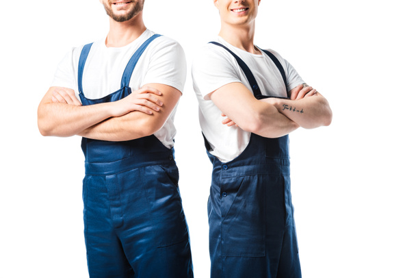 Ausgeschnittene Ansicht zweier lächelnder Mover in Uniform mit vereinzelt auf weiß gekreuzten Armen - Foto, Bild