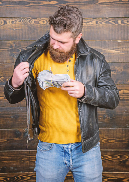 Mafia business. Illegal profit and black cash. Guy mafia dealer with cash profit. Brutal man has cash money. Richness and wellbeing. Man brutal bearded hipster wear leather jacket and hold cash money - Photo, image