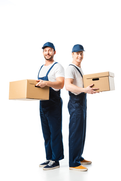 two handsome movers looking at camera while transporting cardboard boxes on white - 写真・画像