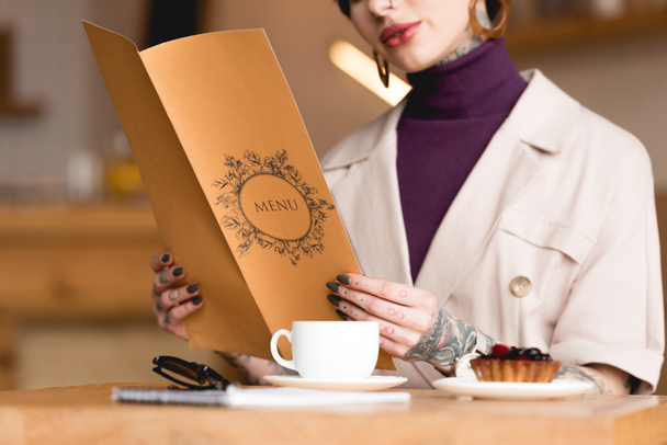 partial view of businesswoman holding menu while sitting at table in cafeteria - Photo, Image