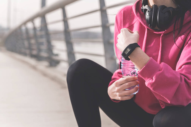 Cropped view of female hands holding bottle of water and sports watch - Photo, Image