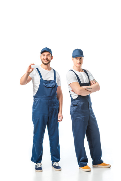movers in uniform looking at camera and showing card with copy space on white - 写真・画像