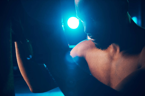 Close-up portrait of concentrated boxer on the ring. Studio shot, blue light. Light projectors behind man - Foto, immagini