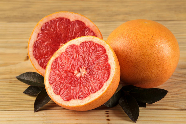 Zitrusfrüchte. frische Grapefruit mit Blättern auf einem natürlichen Holztisch. Nahaufnahme - Foto, Bild