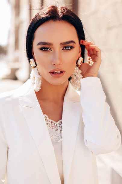 beautiful woman with dark hair in elegant white suit and accesso - Foto, imagen