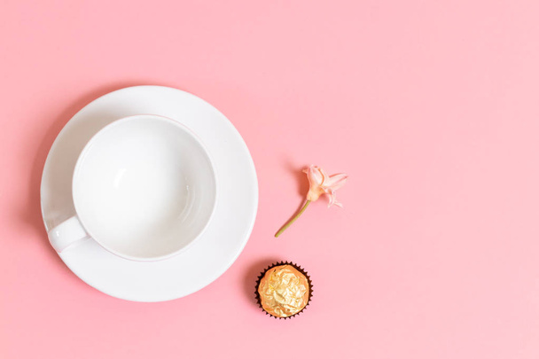 Taza para café o té, dulces y una flor sobre un fondo rosado. Composición de vista superior plana mínima
 - Foto, imagen