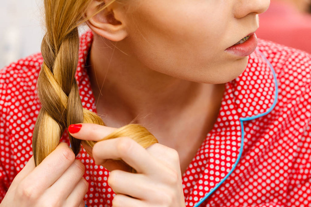 Woman doing braid on blonde hair - Фото, изображение
