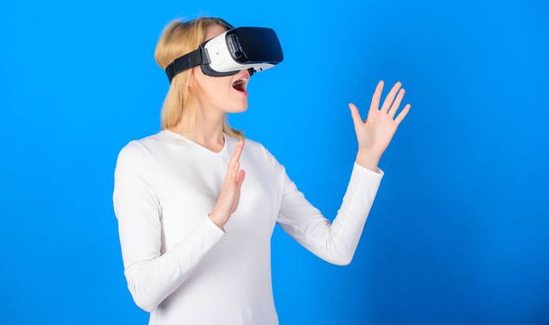 Cheerful smiling woman looking in VR glasses. Confident young woman adjusting her virtual reality headset and smiling. Amazed young woman touching the air during the VR experience. - Photo, image