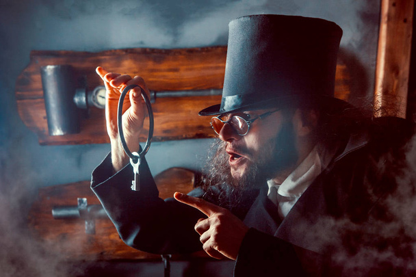 Close up portrait of a gentleman holding up a vintage key. - Zdjęcie, obraz