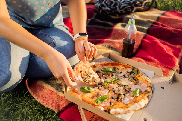 Joyeux jeune femme tenant une pizza chaude en boîte, siège en plein air dans le parc
 - Photo, image