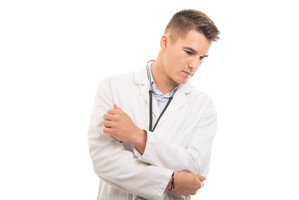 Portrait of young handsome doctor holding elbow like hurting - Photo, image