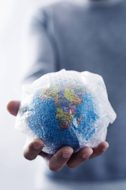 man with a world globe wrapped in bubble wrap - Photo, Image