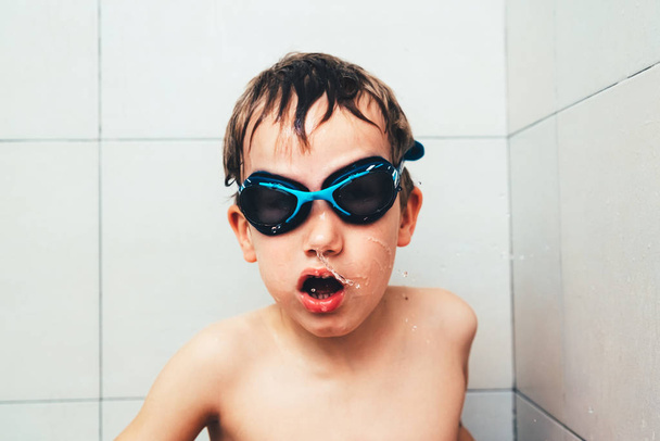 Portrait of boy in a bathtub with diving goggles putting funny f - Fotó, kép