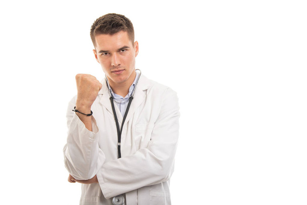 Portrait of young handsome doctor showing fist looking mad - Photo, Image