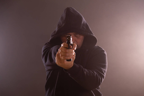 Uomo con cappuccio nero punta pistola
 - Foto, immagini