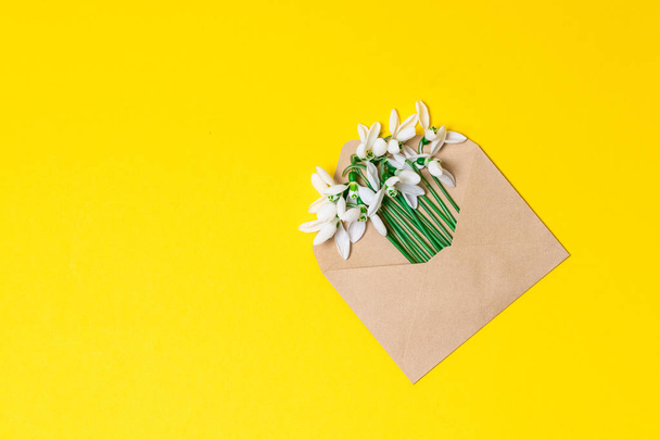 Opened craft paper envelope full of spring blossom flowers on white background. top view. - Fotoğraf, Görsel