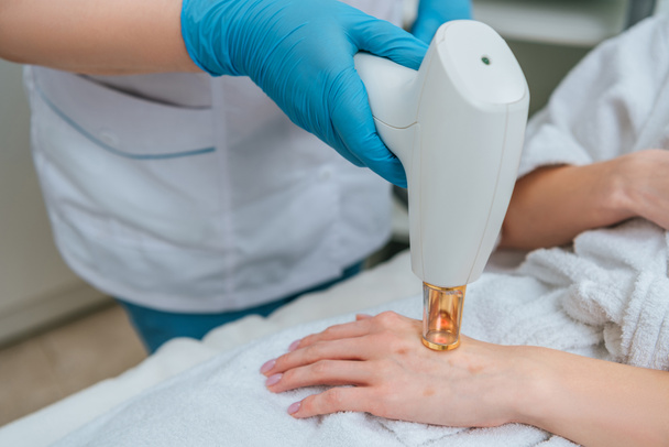 Cropped view of cosmetologist in rubber gloves doing laser treatment - Φωτογραφία, εικόνα