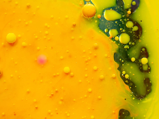 Yellow drops of paint and green ink spots, abstract background. Close up macro shot. Blurred background. Selective soft focus. Colorful universe of paint drops and spots, abstract pattern. - Foto, Bild