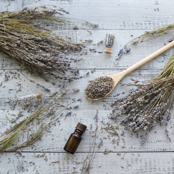 natural dry lavender flowers with organic lavender oil over wooden background - Fotoğraf, Görsel
