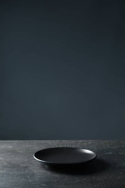 Plate on table against dark background - Foto, imagen
