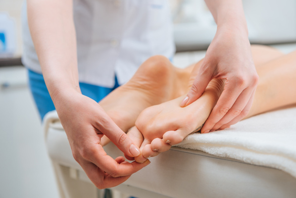Vue recadrée du masseur faisant massage des pieds à la femme sur la table de massage
 - Photo, image