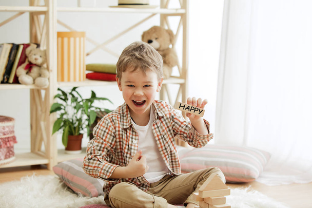 Wooden cubes with word HAPPY in hands of little boy - Foto, imagen