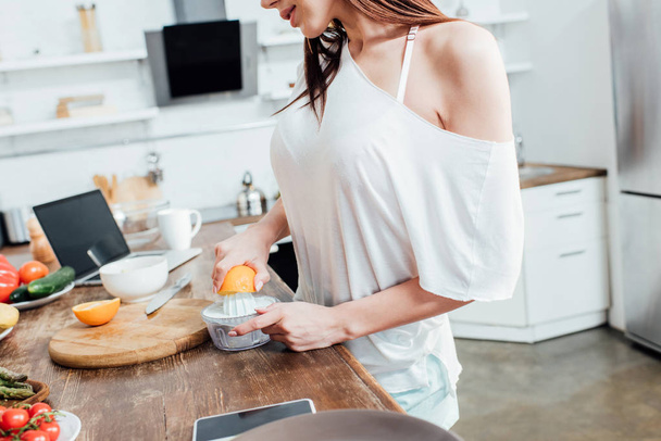 Частковий вигляд жінки, що робить свіжий апельсиновий сік на кухні
 - Фото, зображення