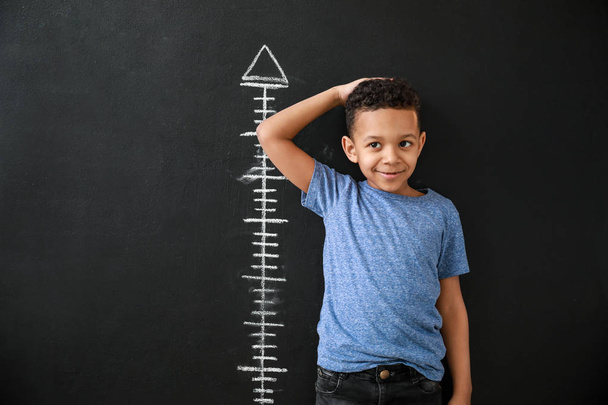 Афроамериканец, измеряющий высоту у темной стены
 - Фото, изображение