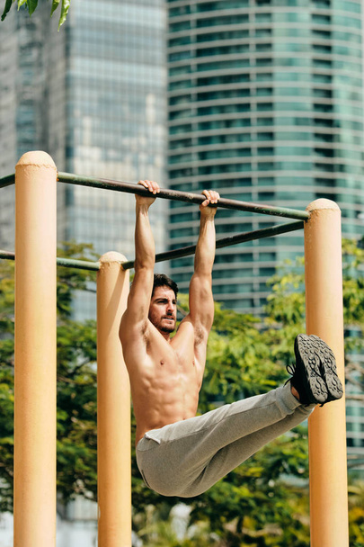 Erwachsener Mann trainiert Bauchmuskeln bei Calisthenics im Freien - Foto, Bild