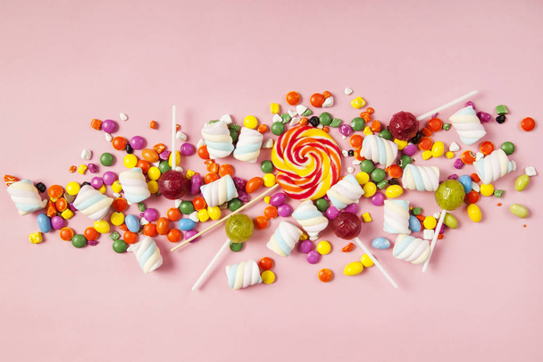 Színes nyalókák és különböző színű kerek cukorka. Felülnézet. - Fotó, kép