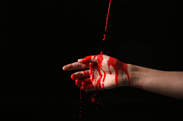 Female hand with pouring paint against dark background - Fotoğraf, Görsel