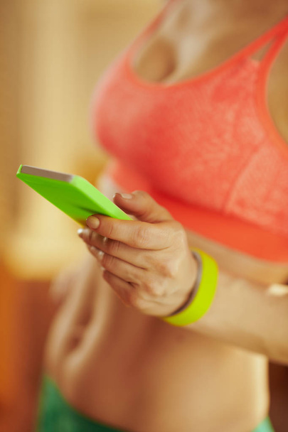 Closeup on smartphone in hand of woman using fitness app - Foto, Imagen