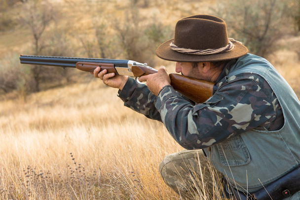 Hunter z kapelusz i broń w poszukiwaniu zdobyczy w stepie, ma na zdobycz - Zdjęcie, obraz