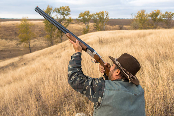Hunter with a hat and a gun in search of prey in the steppe, Aims for prey - Photo, Image