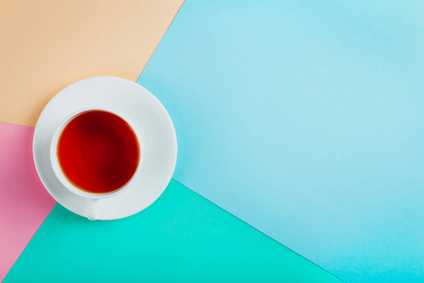 A cup of tea on a pastel colored paper background. Copy space. - 写真・画像