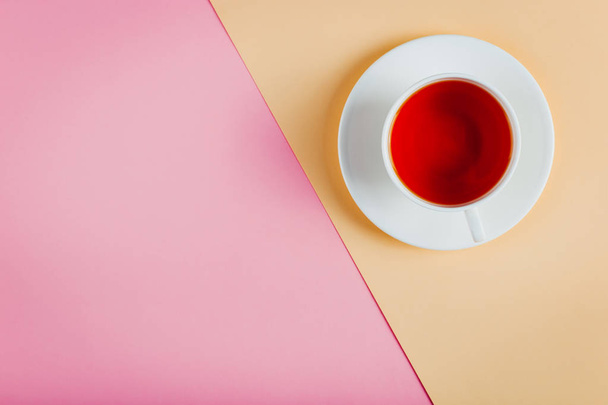 A cup of tea on a pastel colored paper background. Copy space. - 写真・画像