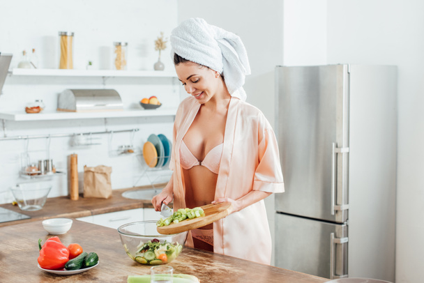 Sexy girl in lingerie and housecoat cooking salad in kitchen - Fotografie, Obrázek