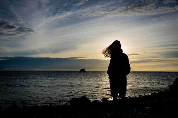 Silhouet van een meisje staan aan kust met mooie hemel op de achtergrond op Harapan Island, Indonesië - Foto, afbeelding