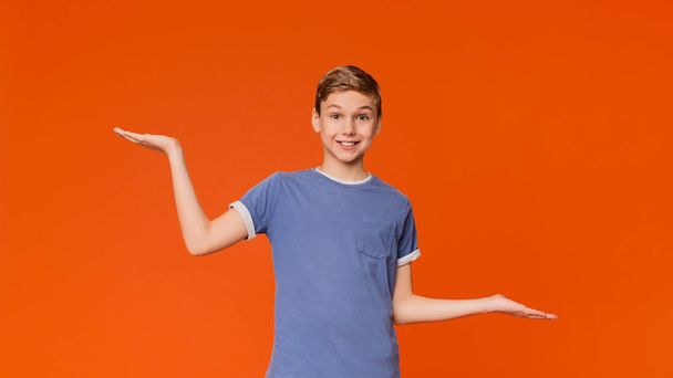 Zögerlicher Junge breitet Hände seitlich mit leerem Raum aus - Foto, Bild