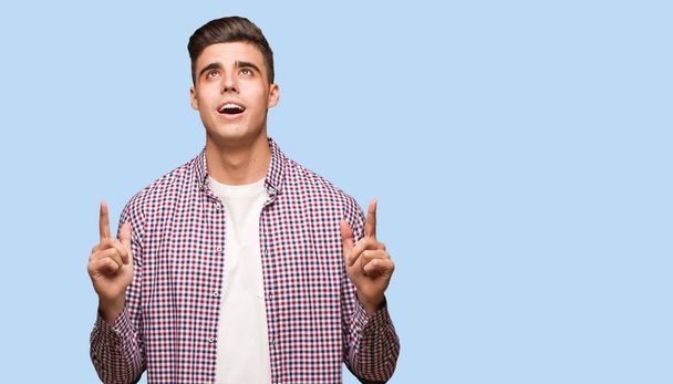 Young cool man surprised pointing up to show something - Photo, Image