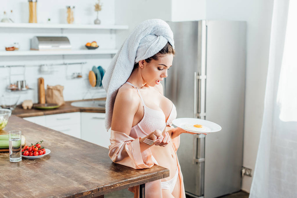 Shocked girl in underwear with towel on head holding plate with fried egg - Foto, Imagen