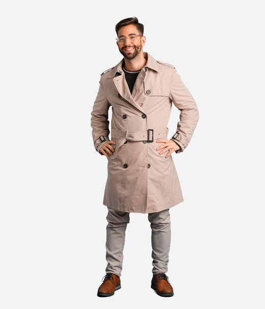 Young man wearing trench coat with hands on hips - Photo, Image
