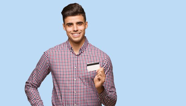 Jovem segurando cartão de crédito com as mãos nos quadris
 - Foto, Imagem