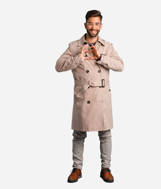 Young man wearing trench coat doing a heart shape with hands - Photo, Image