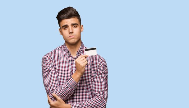 Jonge man met creditcard kijken rechtdoor - Foto, afbeelding