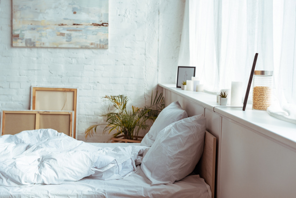 modernes Schlafzimmer mit gemütlichem Bett, Kissen, Decke, Bildern und Pflanzen  - Foto, Bild