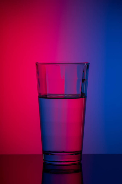 függőleges kép pohár vizet kék rózsaszín háttér - Fotó, kép