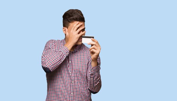 Junger Mann mit Kreditkarte peinlich berührt und gleichzeitig lachend - Foto, Bild